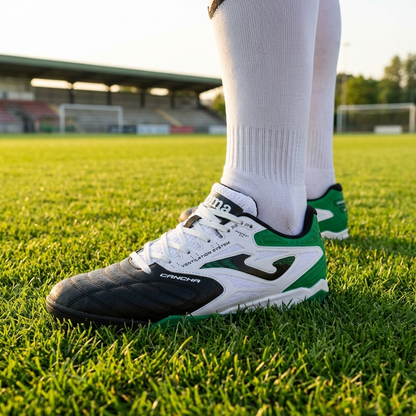 Soccer player's feet wearing green and white cleats on a grass field